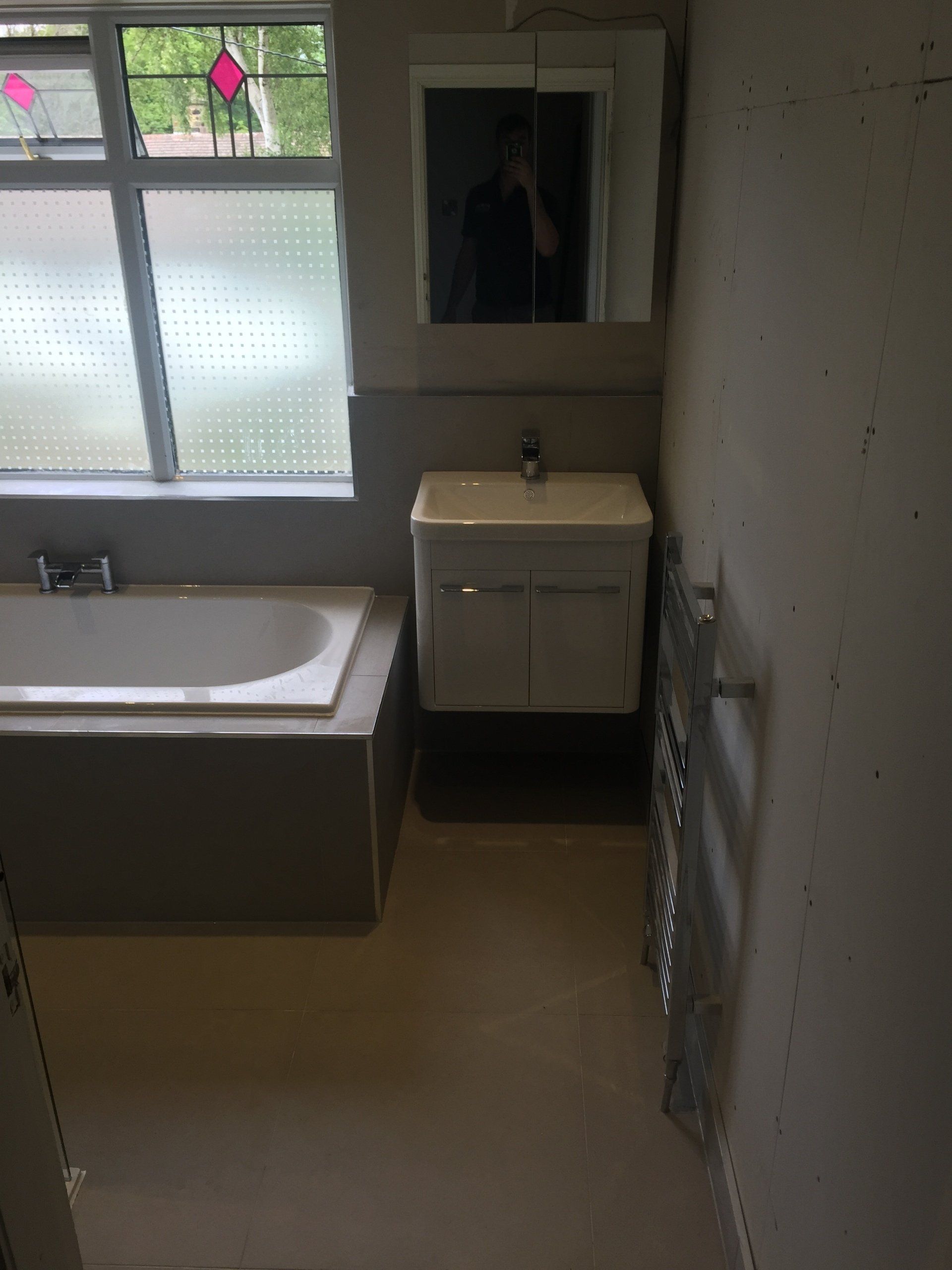 Bathroom with a bathtub, sink, and mirror; neutral color scheme.