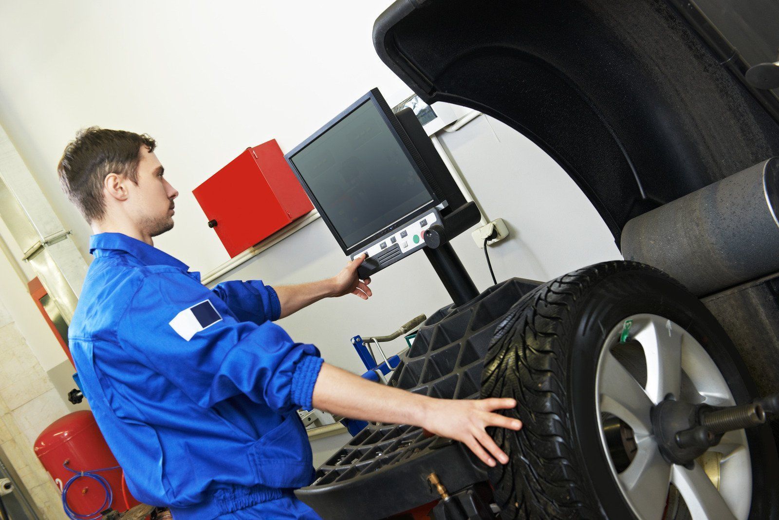 A man in a blue uniform is balancing a tire on a machine.