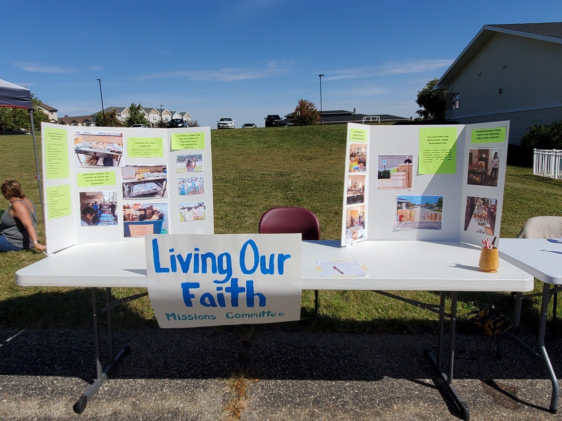 Table at outdoor Ministry Fair displays informational posters .