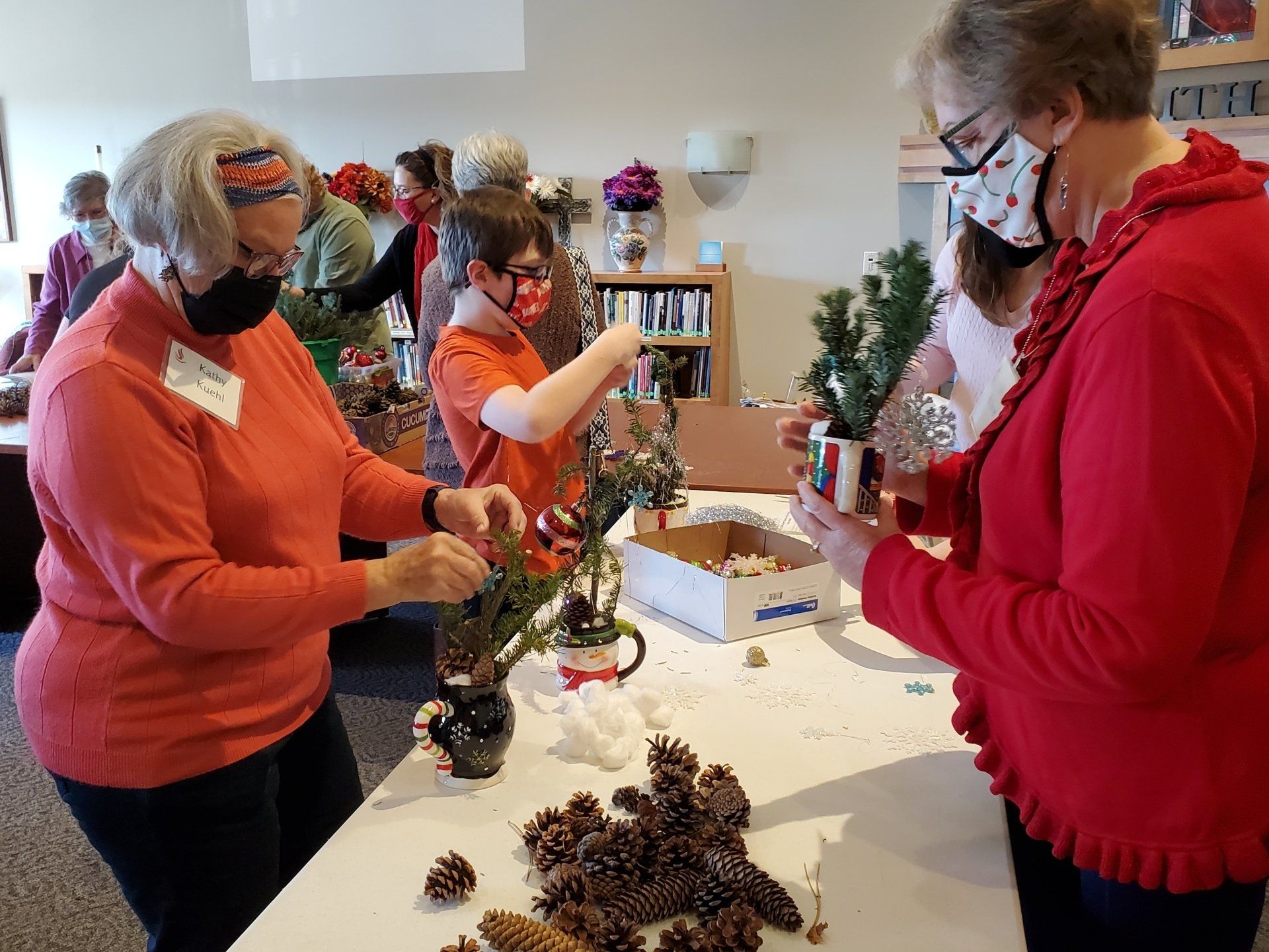 Volunteers decorating mini Christmas trees for nursing home residents.