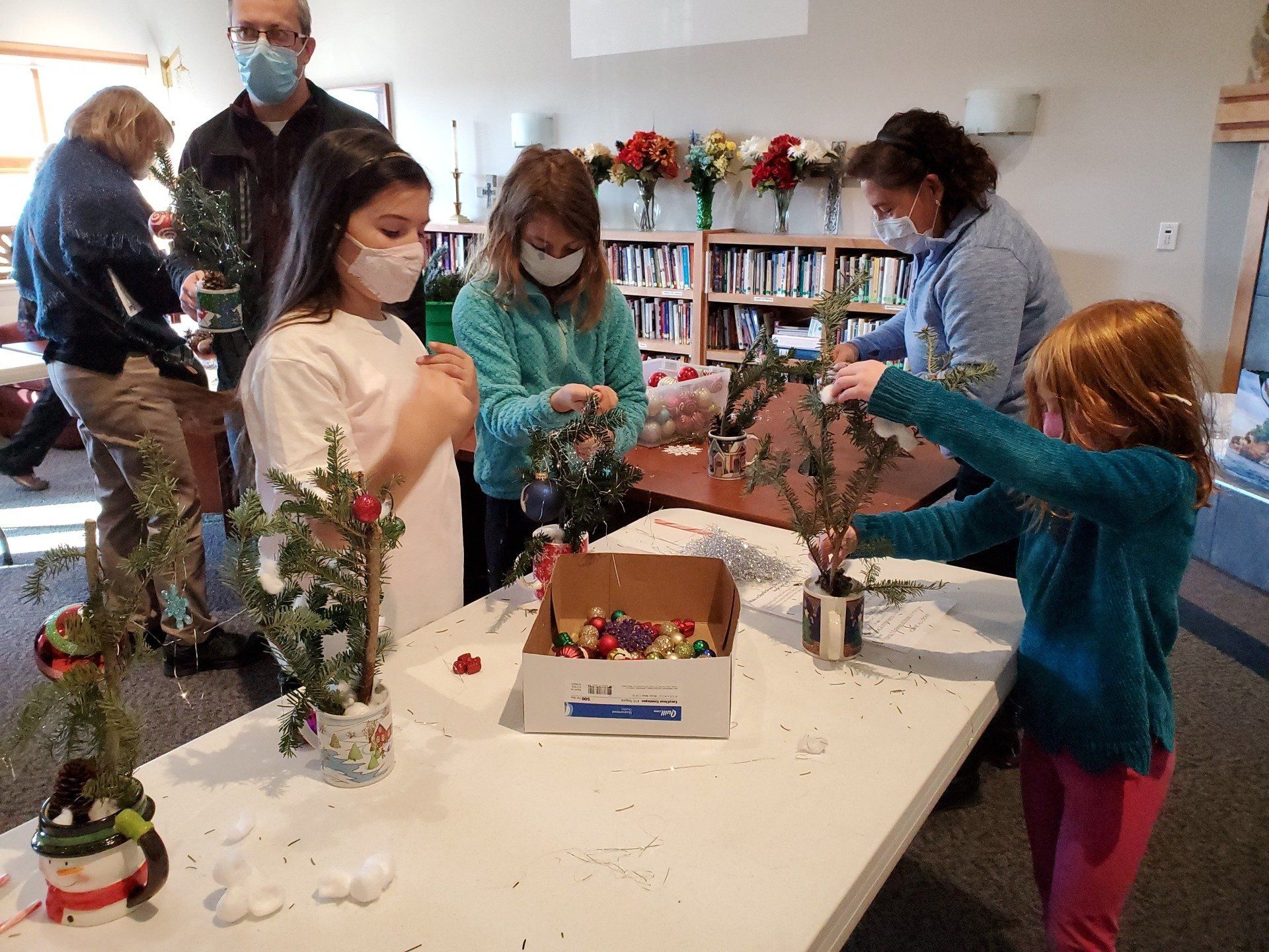 Children and adults making mini Christmas trees for nursing home residents