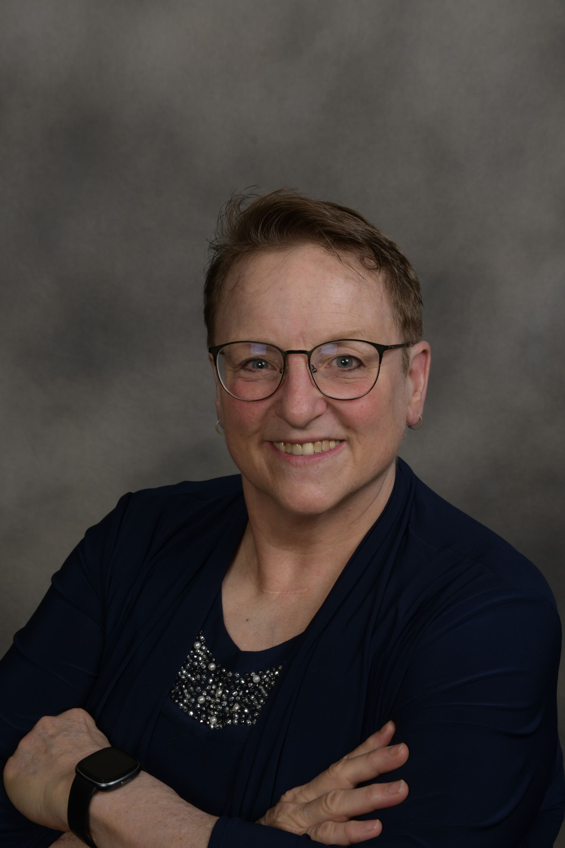 Woman wearing glasses and a yellow shirt smiles.