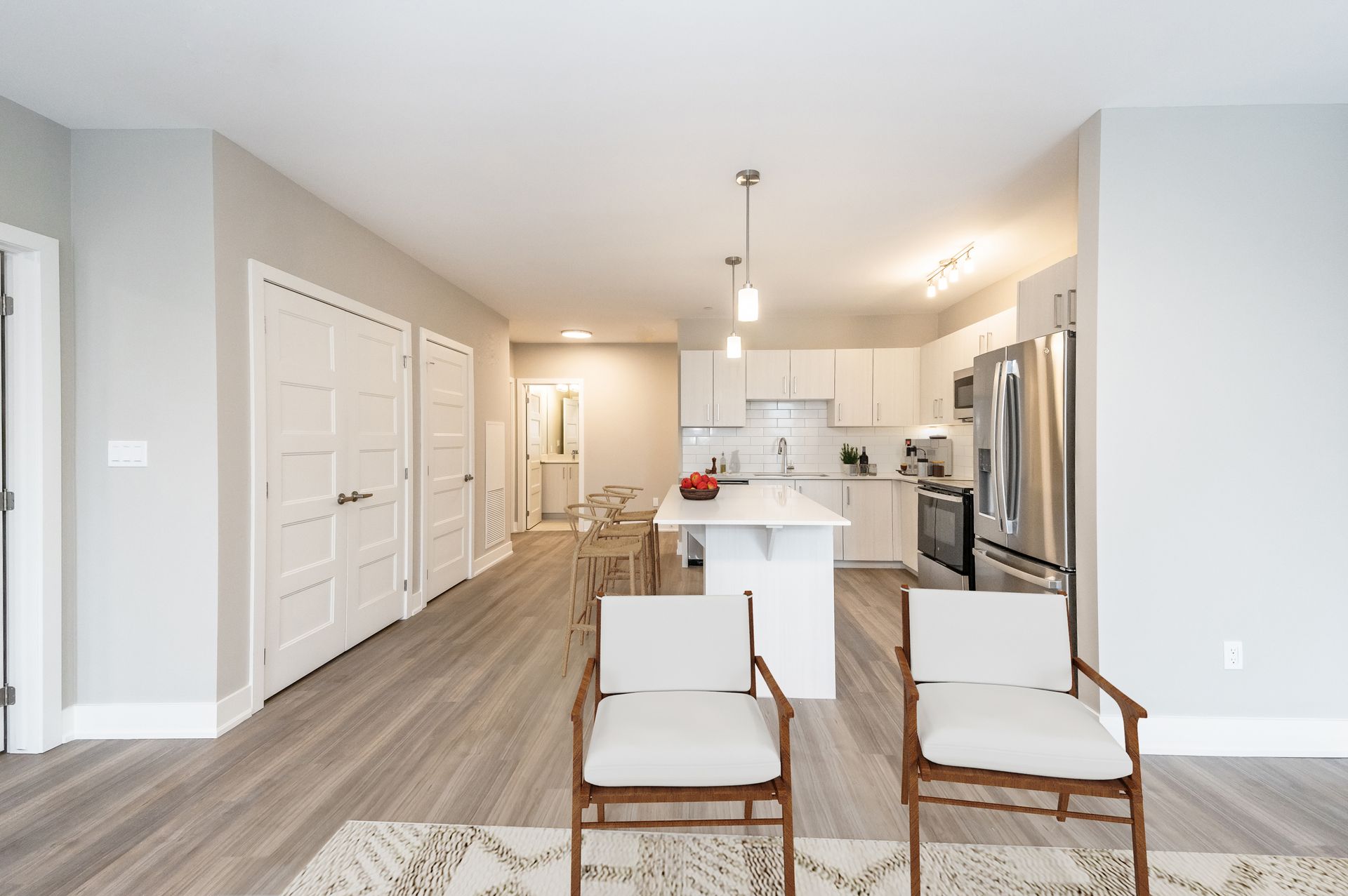 A living room with two chairs and a kitchen in the background
