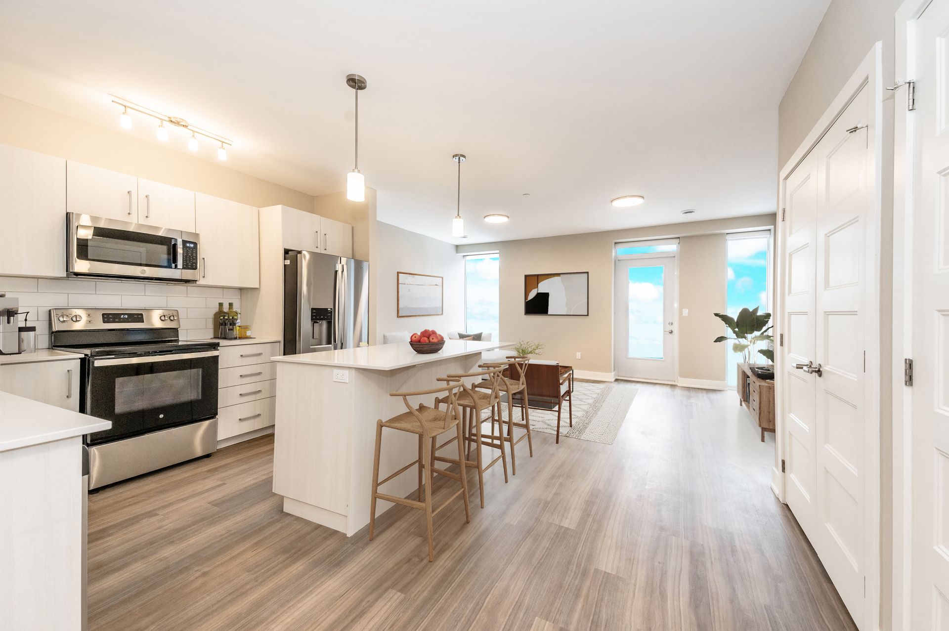 A kitchen with white cabinets , stainless steel appliances , hardwood floors and a large island.