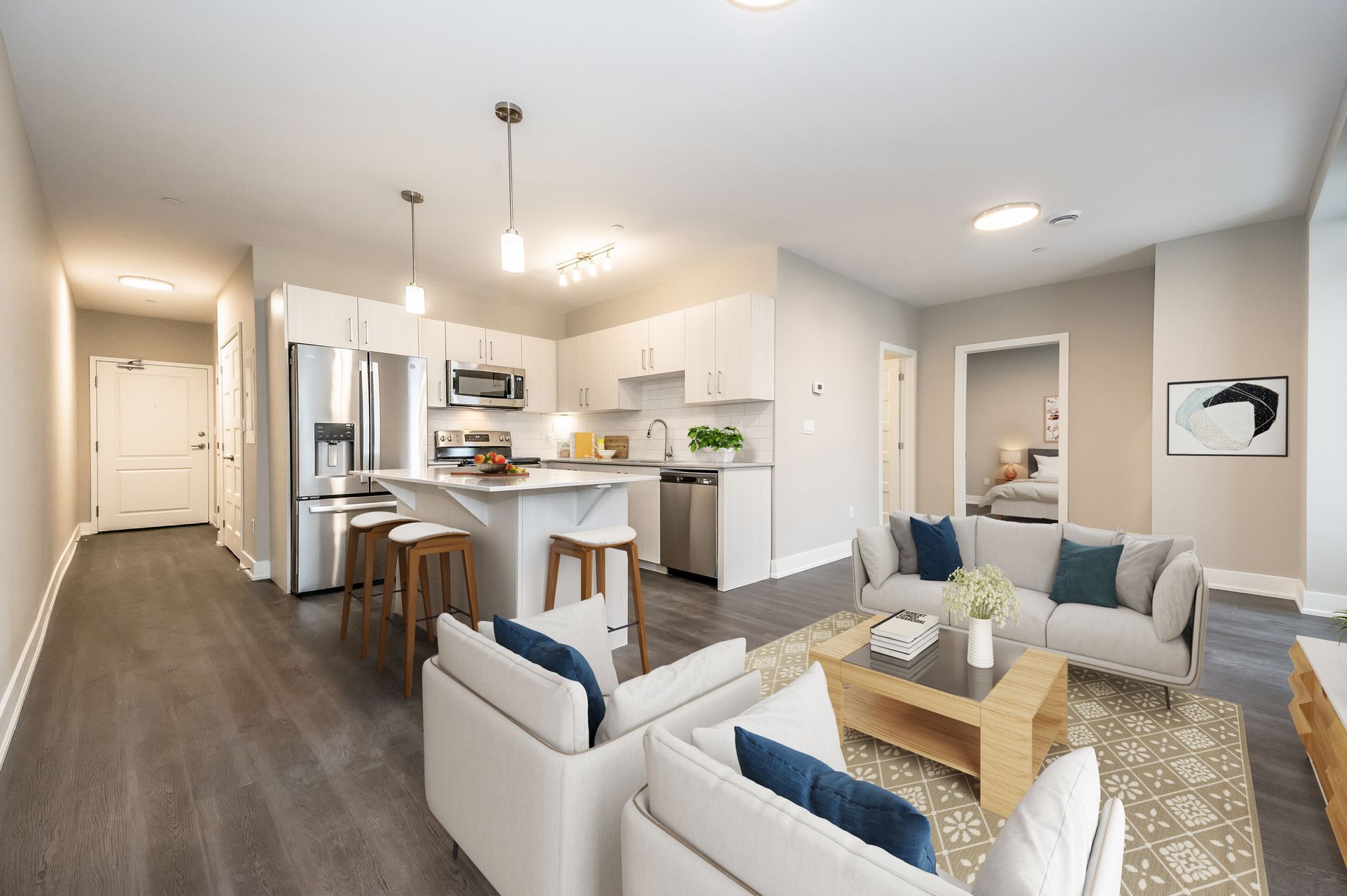 A living room with a couch , chairs , coffee table and kitchen.