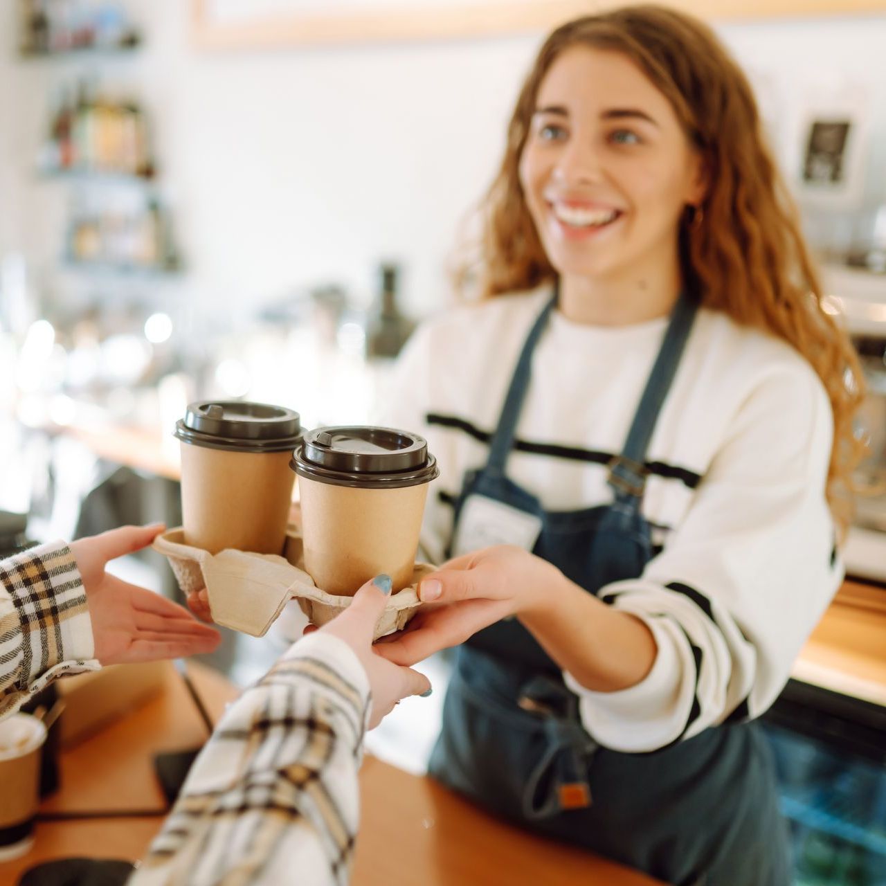 a woman is serving two cups of coffee to a customer