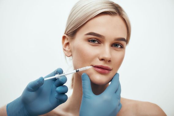 A woman is getting a botox injection in her lips.