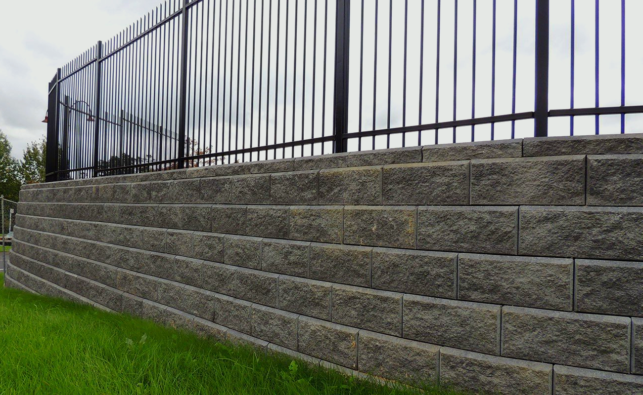 A stone wall with a metal fence on top of it.