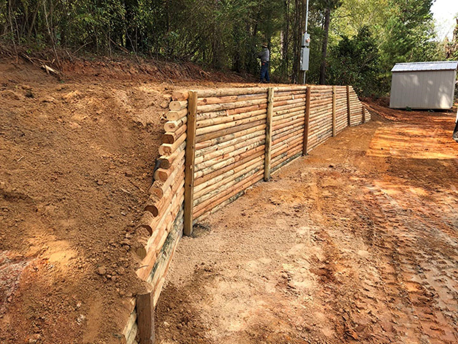 A wooden retaining wall is being built on top of a dirt hill.