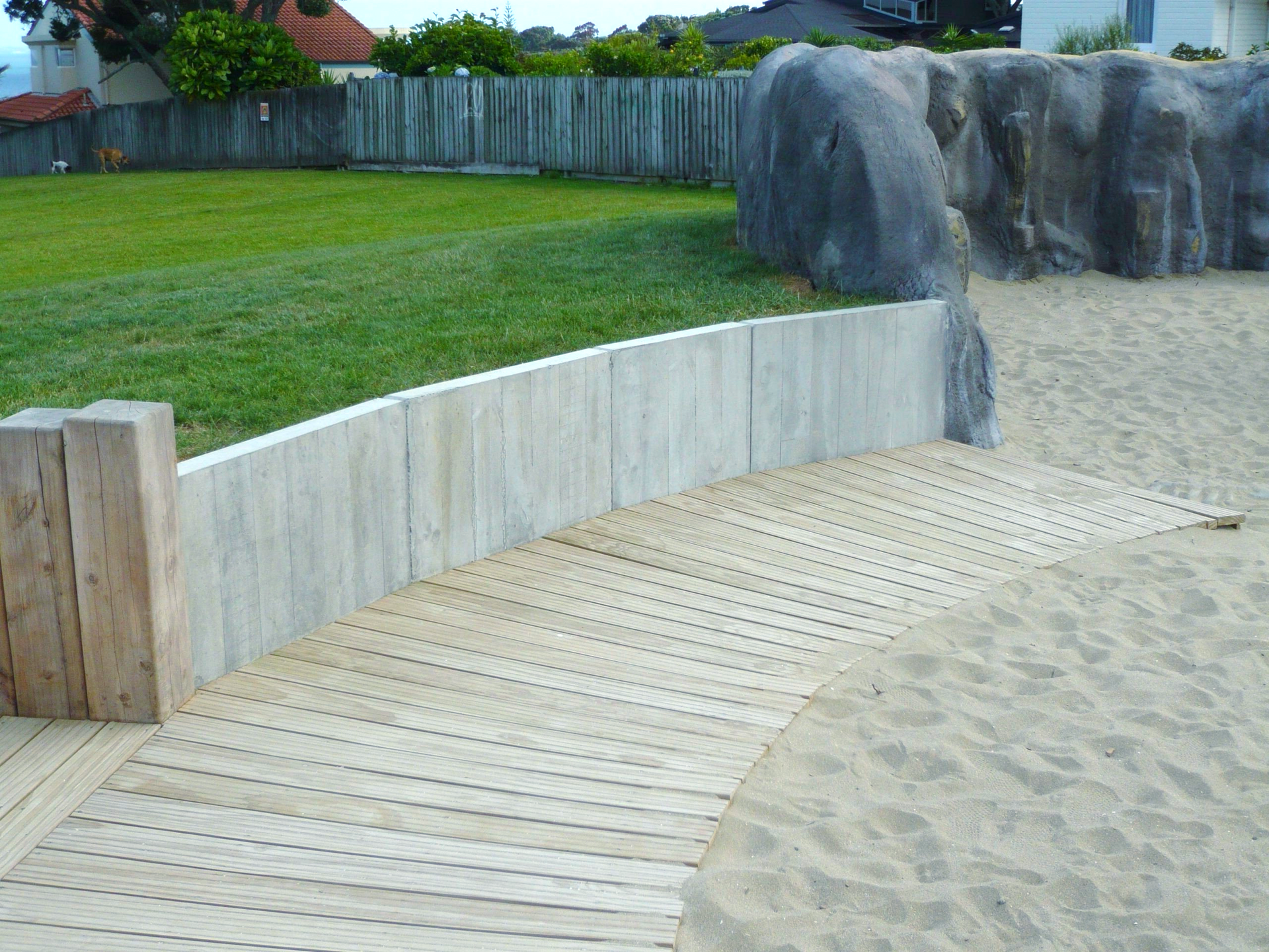 A wooden walkway with a concrete wall next to it.