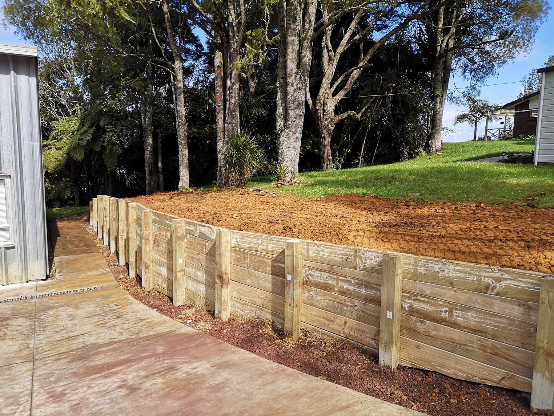 A wooden fence surrounds a lush green field with trees in the background.