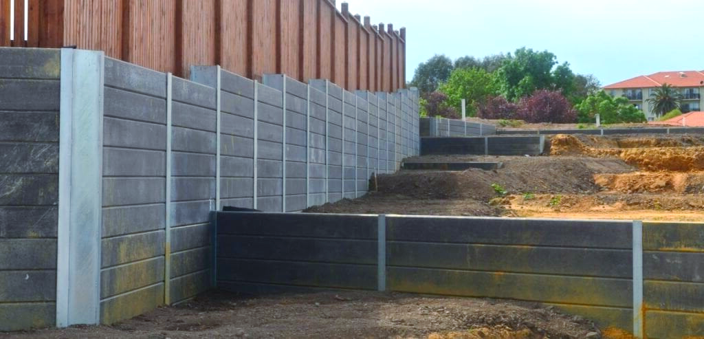 A large concrete wall with a wooden fence surrounding it.