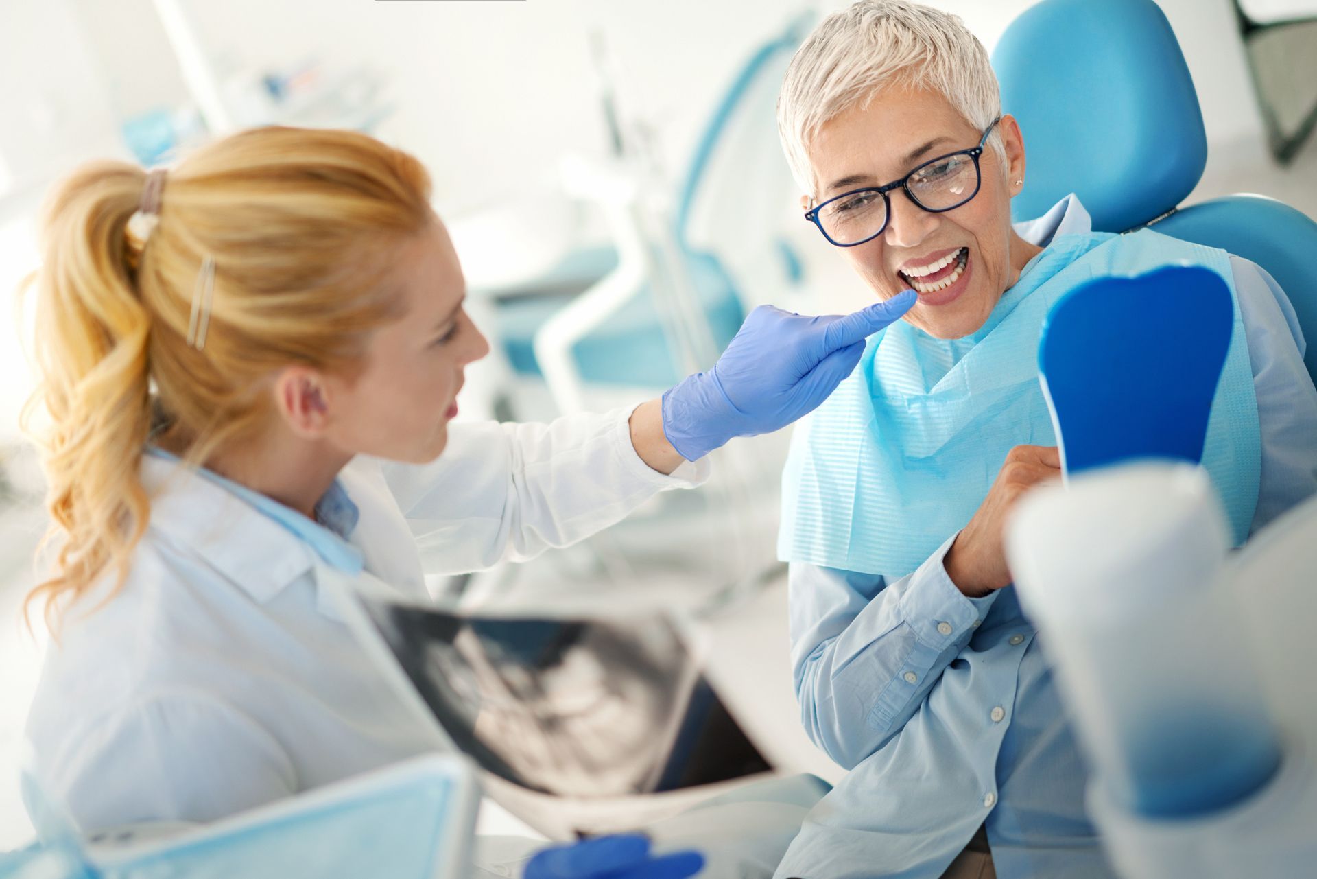 A woman is sitting in a dental chair while a professional dentist examines her teeth.