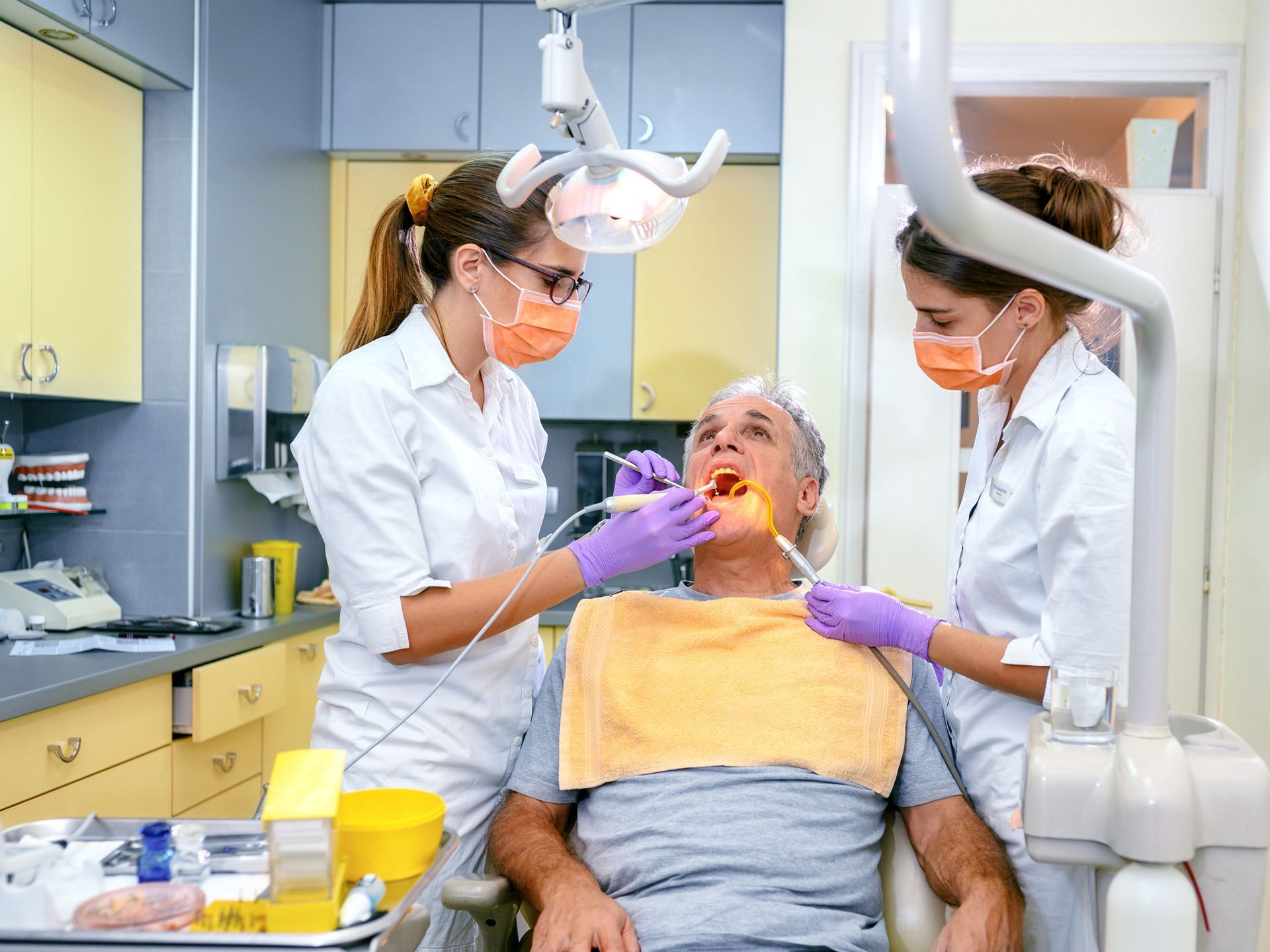 A man is getting his teeth examined by two dentists.