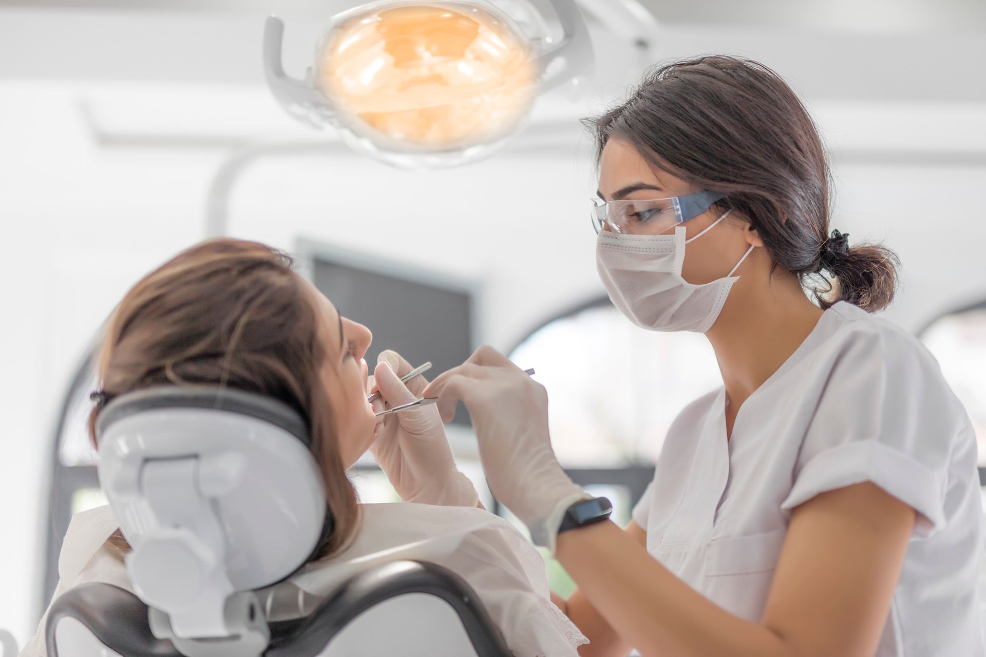 A female dentist is examining a woman 's teeth in a dental office.