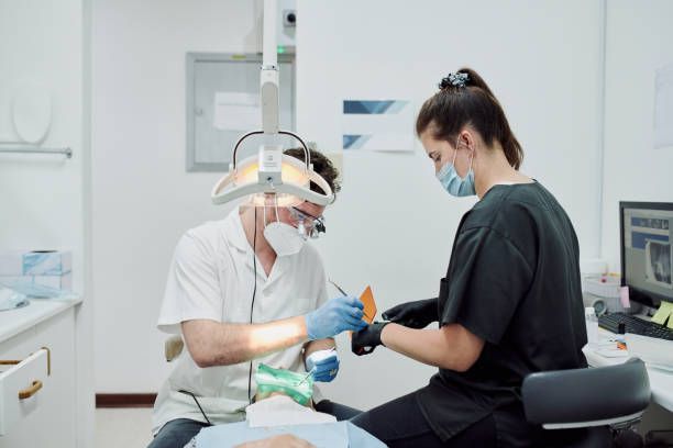 A dentist and a nurse are working on a patient 's teeth in a dental office.