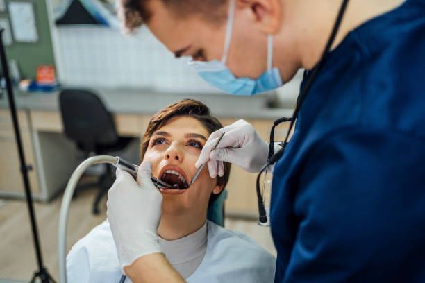 A dentist is examining a woman 's teeth in a dental office.