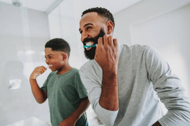 A man and a boy are brushing their teeth in a bathroom.