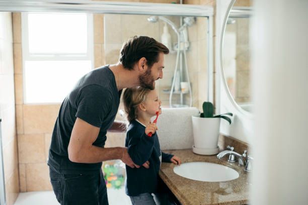 A man and a child are brushing their teeth in a bathroom.