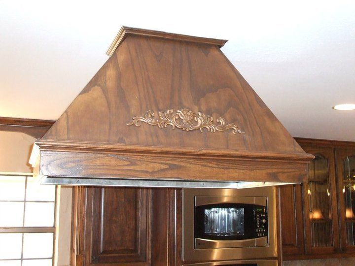 A kitchen with a wooden hood and a stainless steel microwave