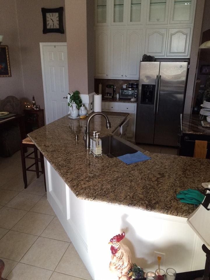 A kitchen with granite counter tops and a stainless steel refrigerator