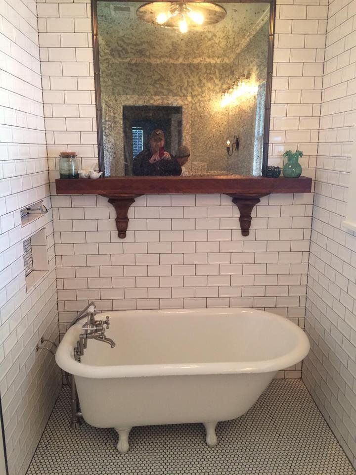 A bathtub in a bathroom with a mirror above it