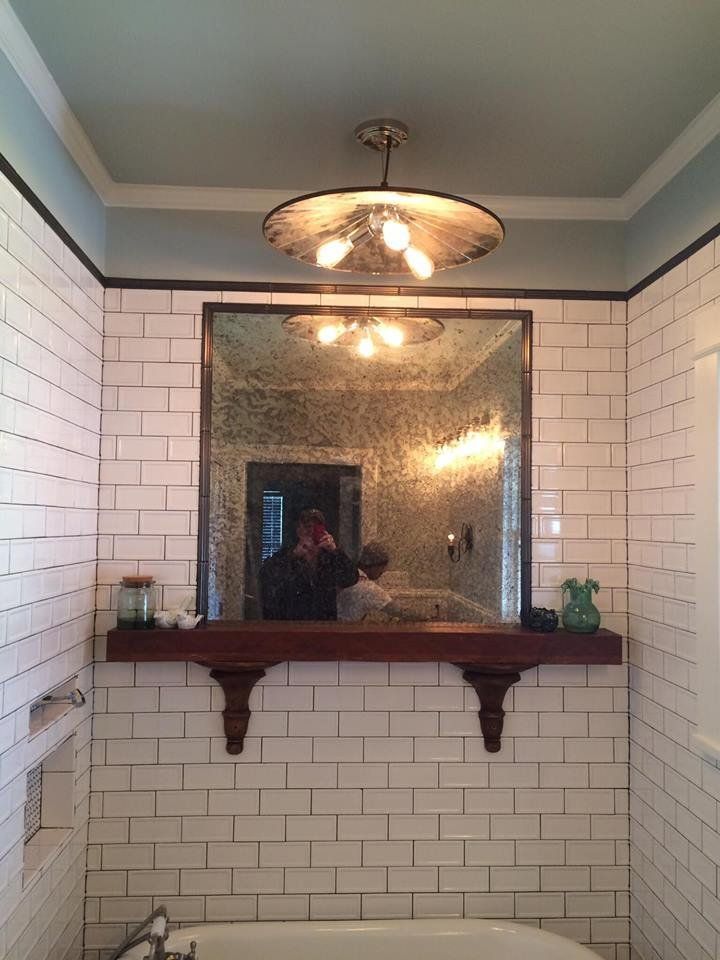 A bathroom with white tiles and a large mirror