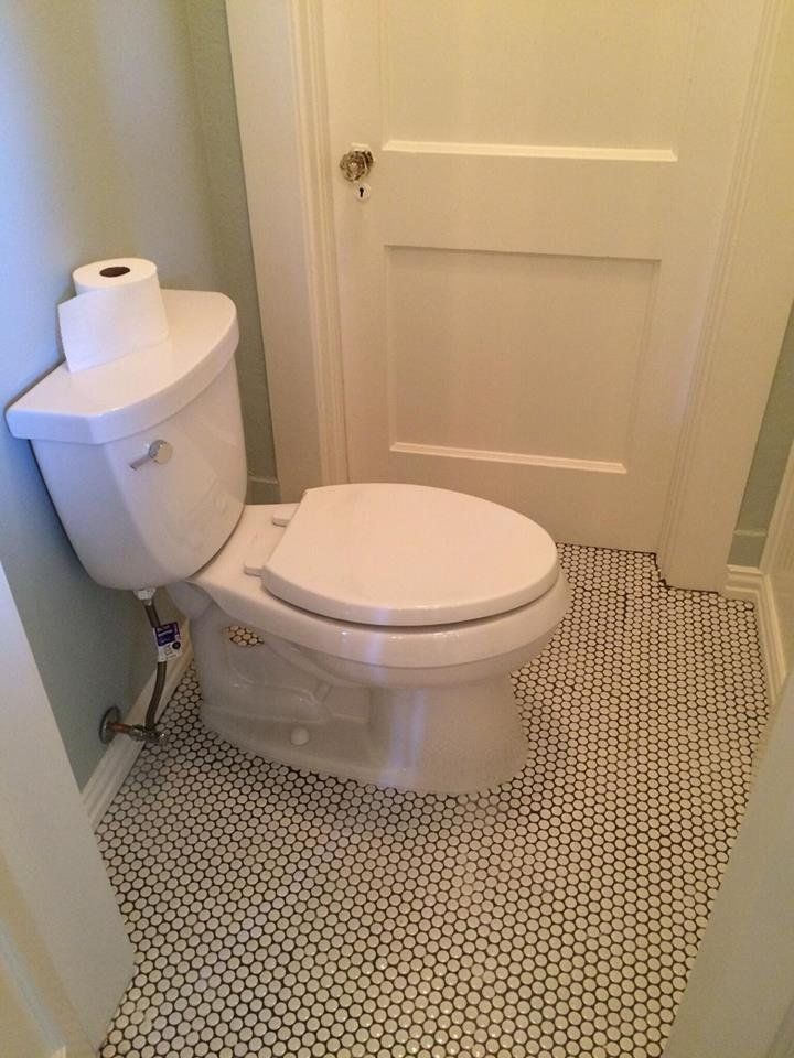 A toilet is sitting in a bathroom next to a door.