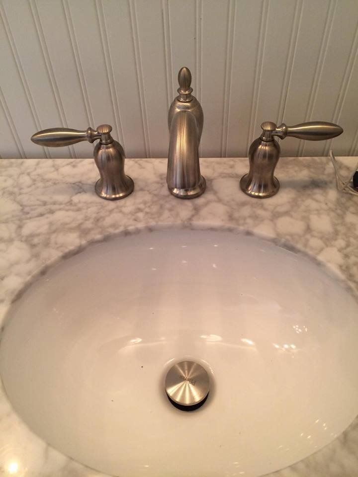 A bathroom sink with a faucet and drain on a marble counter top.