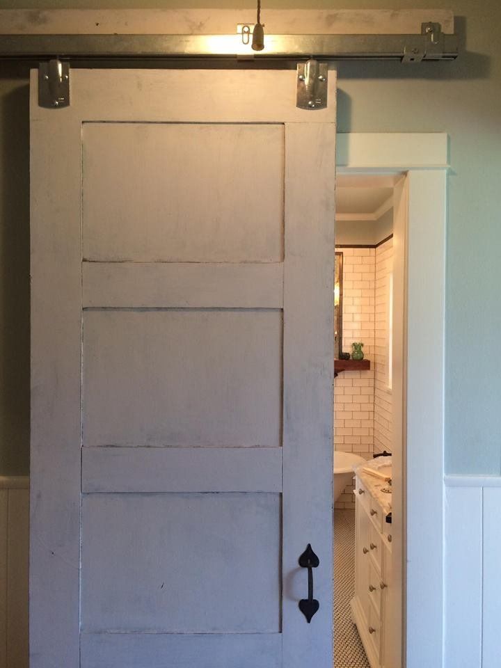 A white sliding barn door is open to a bathroom