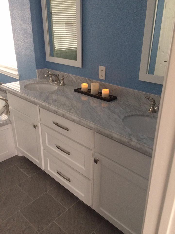 A bathroom with two sinks , a mirror and candles on the counter.