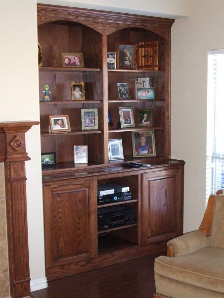 A living room with a fireplace and shelves filled with pictures