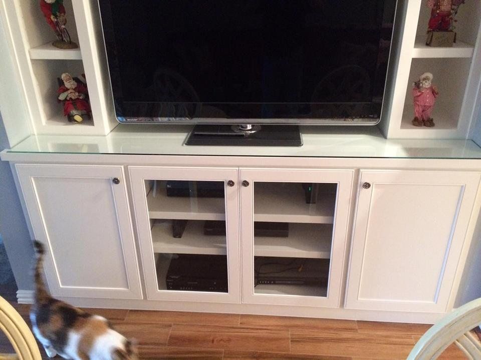 A cat is standing in front of a tv on a entertainment center