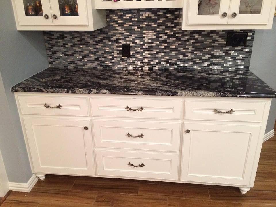 A kitchen with white cabinets and black granite counter tops.