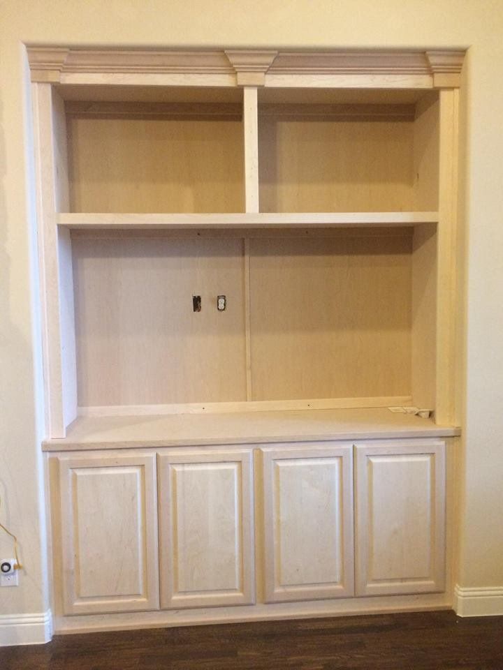 A built in entertainment center with white cabinets and shelves