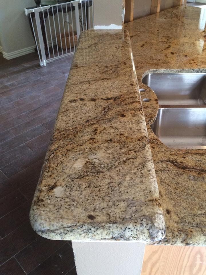 A kitchen with a granite counter top and a stainless steel sink.