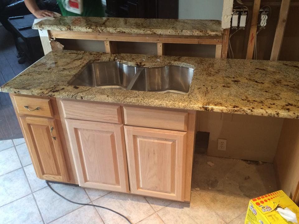 A kitchen with granite counter tops and a stainless steel sink