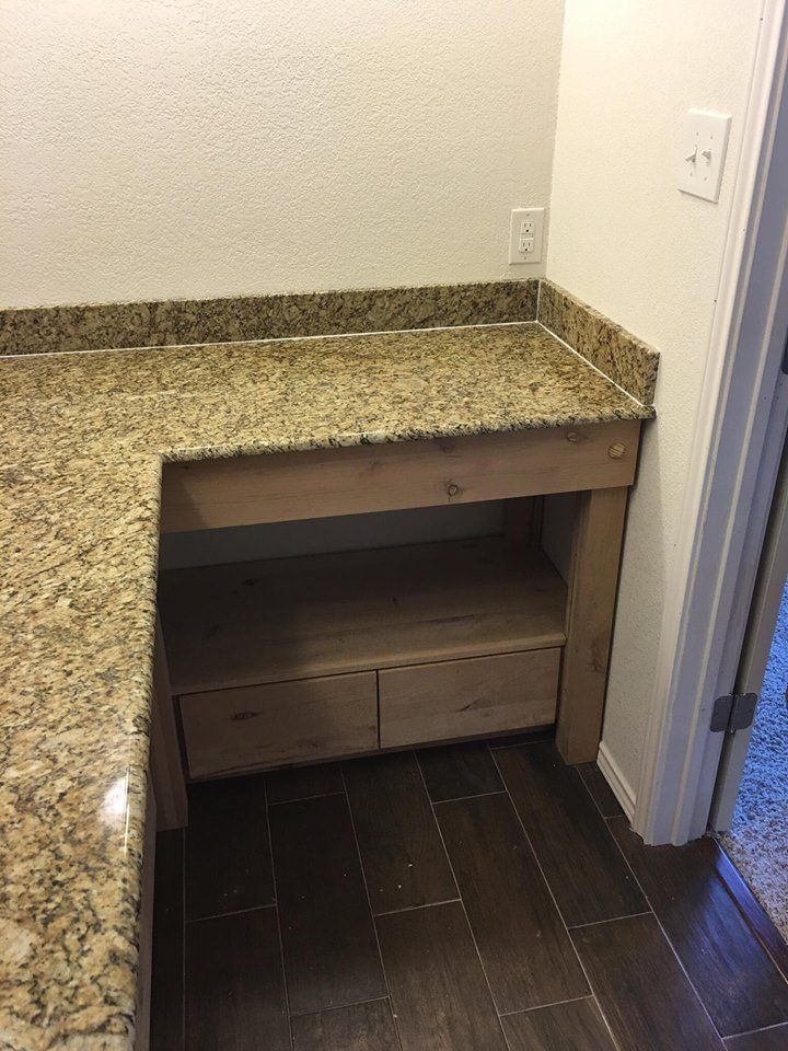 A bathroom vanity with a granite counter top and wooden drawers.
