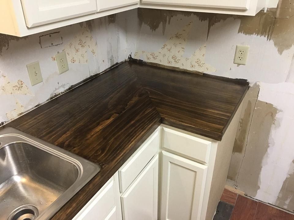 A kitchen with a sink , cabinets and a wooden counter top.