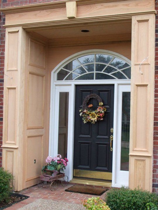A black door with a wreath hanging on it