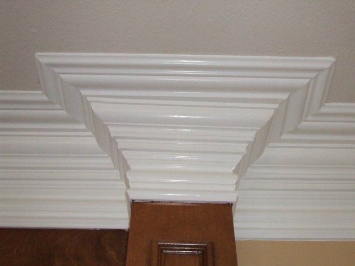 A ceiling with white molding and a wooden door