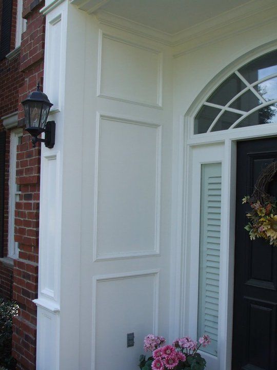 A black door with a wreath on it is next to a white door