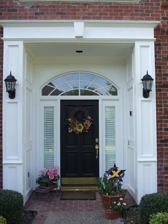 The front door of a brick house has a wreath on it