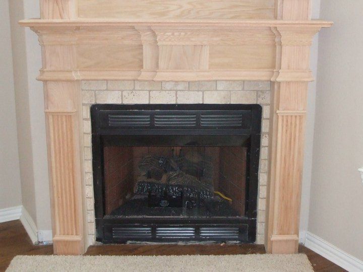 A fireplace with a wooden mantle in a living room
