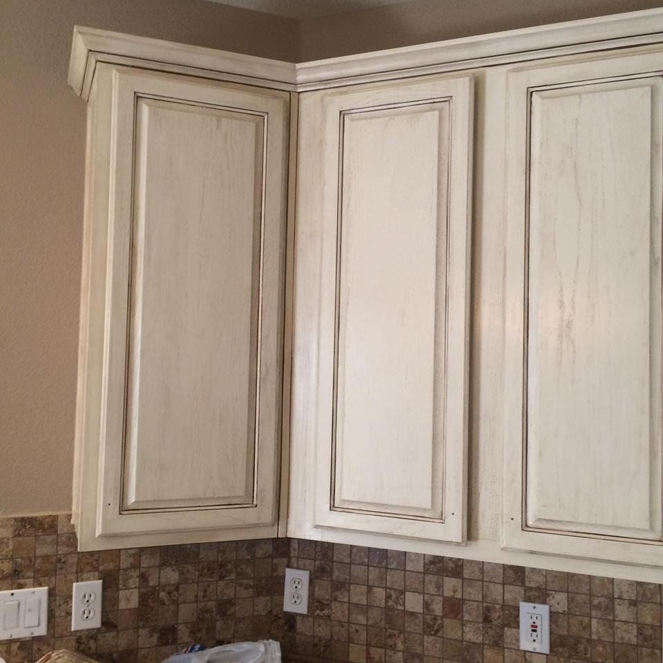 A kitchen with white cabinets and brown tiles