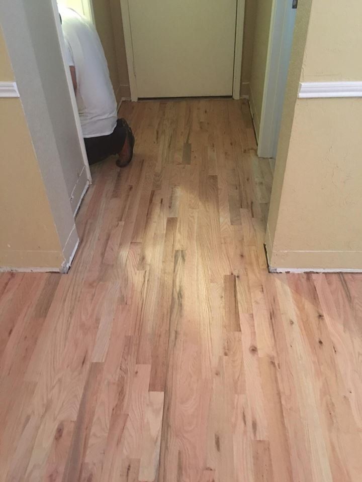 A person is standing on a wooden floor in a hallway.