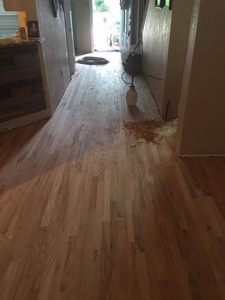 A wooden floor in a living room with a vacuum cleaner on it.