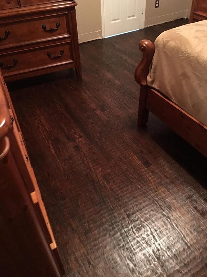 A bedroom with a bed , dresser , and hardwood floor.