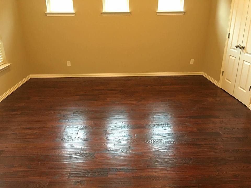 An empty room with hardwood floors and three windows.