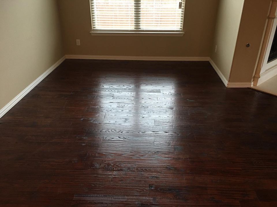 An empty living room with hardwood floors and a window.